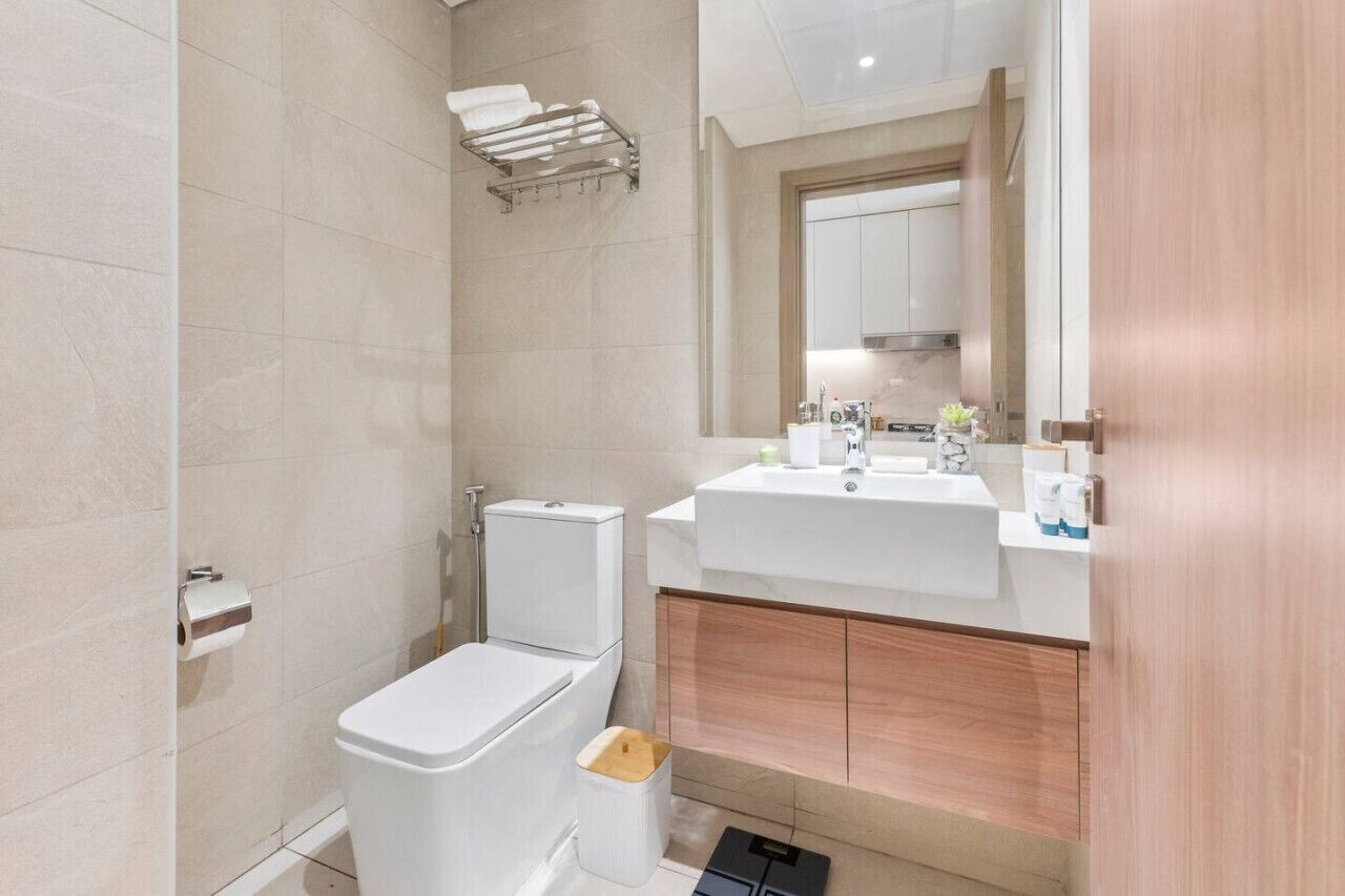 A modern bathroom with a toilet, sink, and mirror.