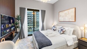 A modern hotel room with a large bed, a TV displaying a Netflix interface, a balcony with curtains, and a contemporary light fixture. - Charming Chalet Escape (Dubai)