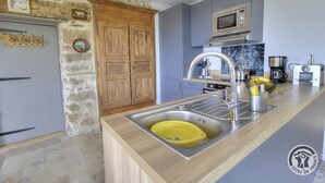 Een moderne keuken met een stenen muur, houten keukenkastjes, een ingebouwde magnetron en een spoelbak met een geel afdruignes.