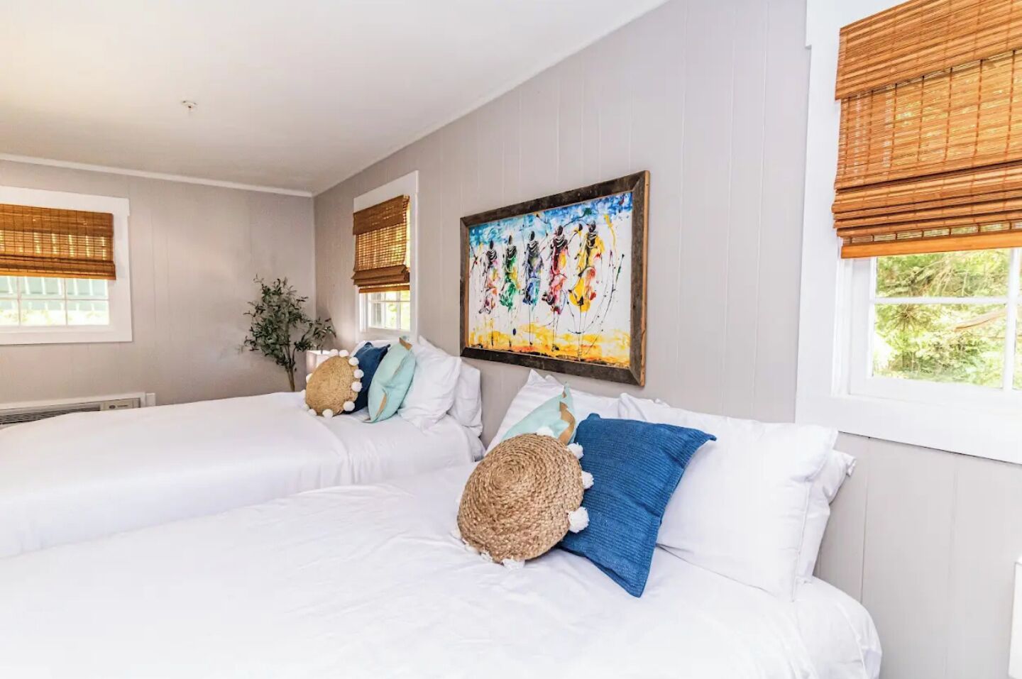 A hotel room with two beds, white bedding, and a painting on the wall.