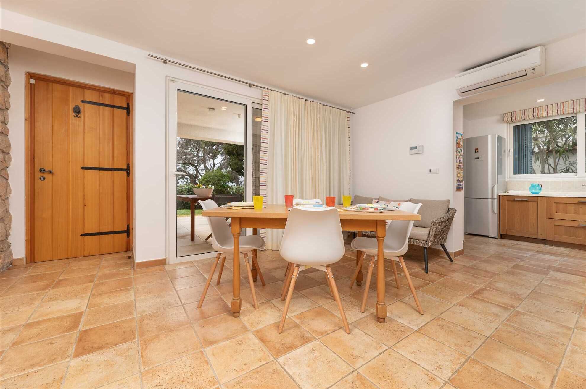 Een moderne keuken met een eethoek, met een houten tafel, witte stoelen en een groot raam met gordijnen.