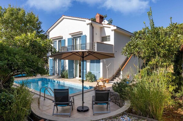 Una casa a due piani con piscina, area relax all'aperto e una scala che conduce al piano superiore.