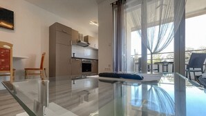 A modern kitchen with a glass dining table, a sofa, and a view of the outdoors. - Awesome apartment in Bibinje with WiFi (Bibinje)