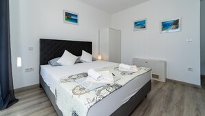 A modern bedroom with a large bed, a dark headboard, and a view of the sea through the window. - Awesome apartment in Bibinje with WiFi (Bibinje)