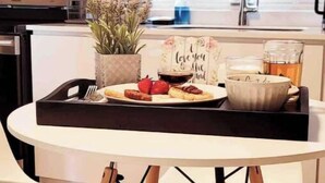 Una cocina moderna con una mesa de comedor redonda, una bandeja con comida y bebidas, y un letrero decorativo.