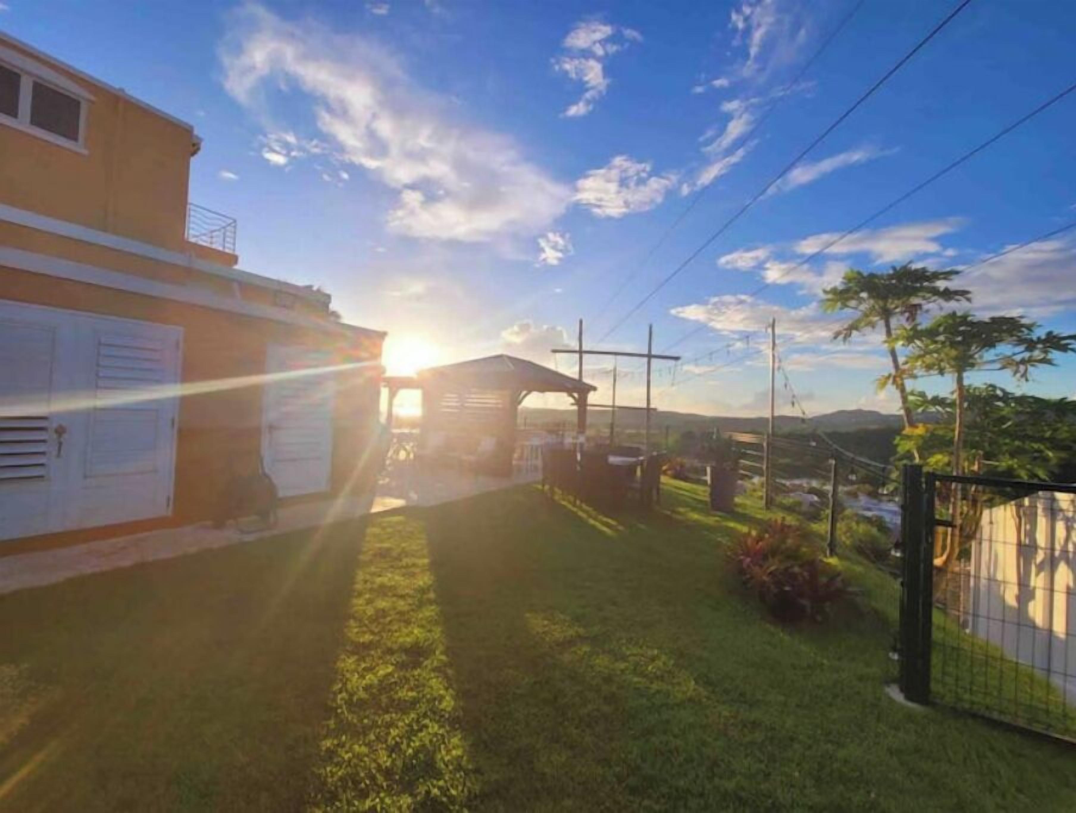 A residential property with a well-maintained lawn, a wooden fence, and a clear view of the surrounding landscape.