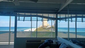 A room with large windows overlooking a beach and cityscape. - COUPLES GETAWAY,HONEYMOON SWEET,Beach Front Condo,kitchen,pool,FREE Prkng,GREAT! (Panama City Beach)