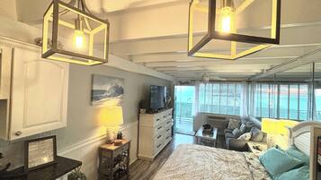 A bedroom with a bed, a dresser, a TV, and a window with blinds.