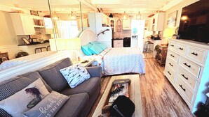 A compact, well-lit room with a bed, a sofa, a desk, and a kitchenette. - COUPLES GETAWAY,HONEYMOON SWEET,Beach Front Condo,kitchen,pool,FREE Prkng,GREAT! (Panama City Beach)