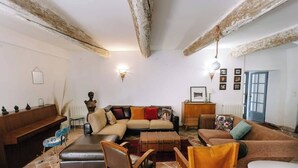 Un salon confortable avec un canapé, des fauteuils, une petite table et un piano.