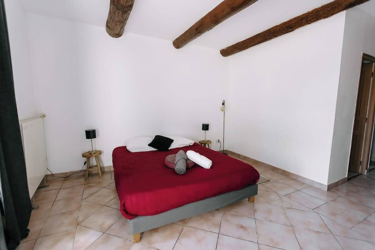 Een slaapkamer met een bed, twee nachtkastjes, een radiator en een houten balk in het plafond.