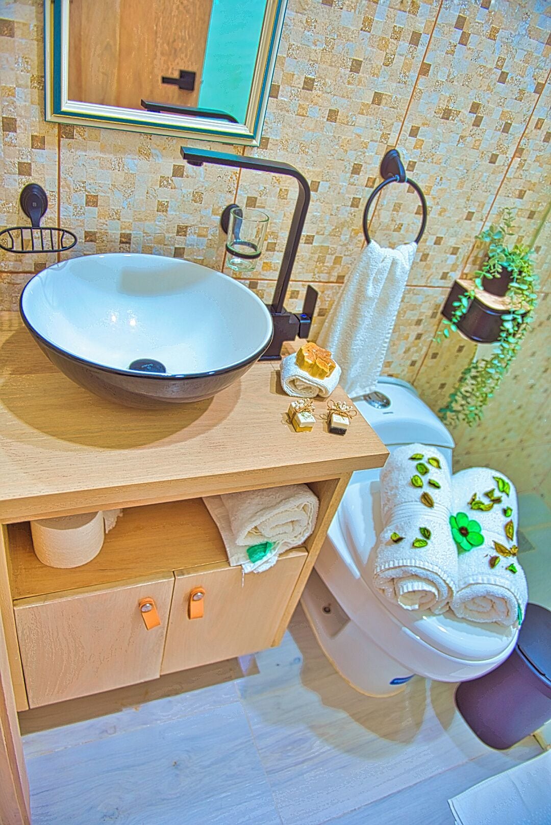 A bathroom with a wooden vanity, a white sink, a towel rack, and a toilet.