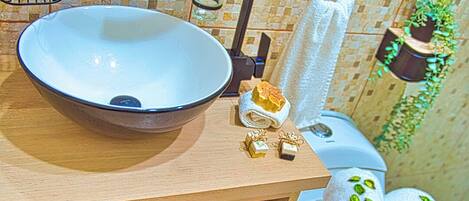 A bathroom with a wooden vanity, a white sink, a towel rack, and a toilet.