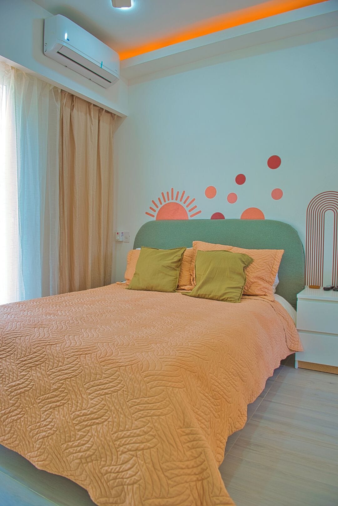 A bedroom with a bed, a nightstand, an air conditioning unit, and a wall decoration.