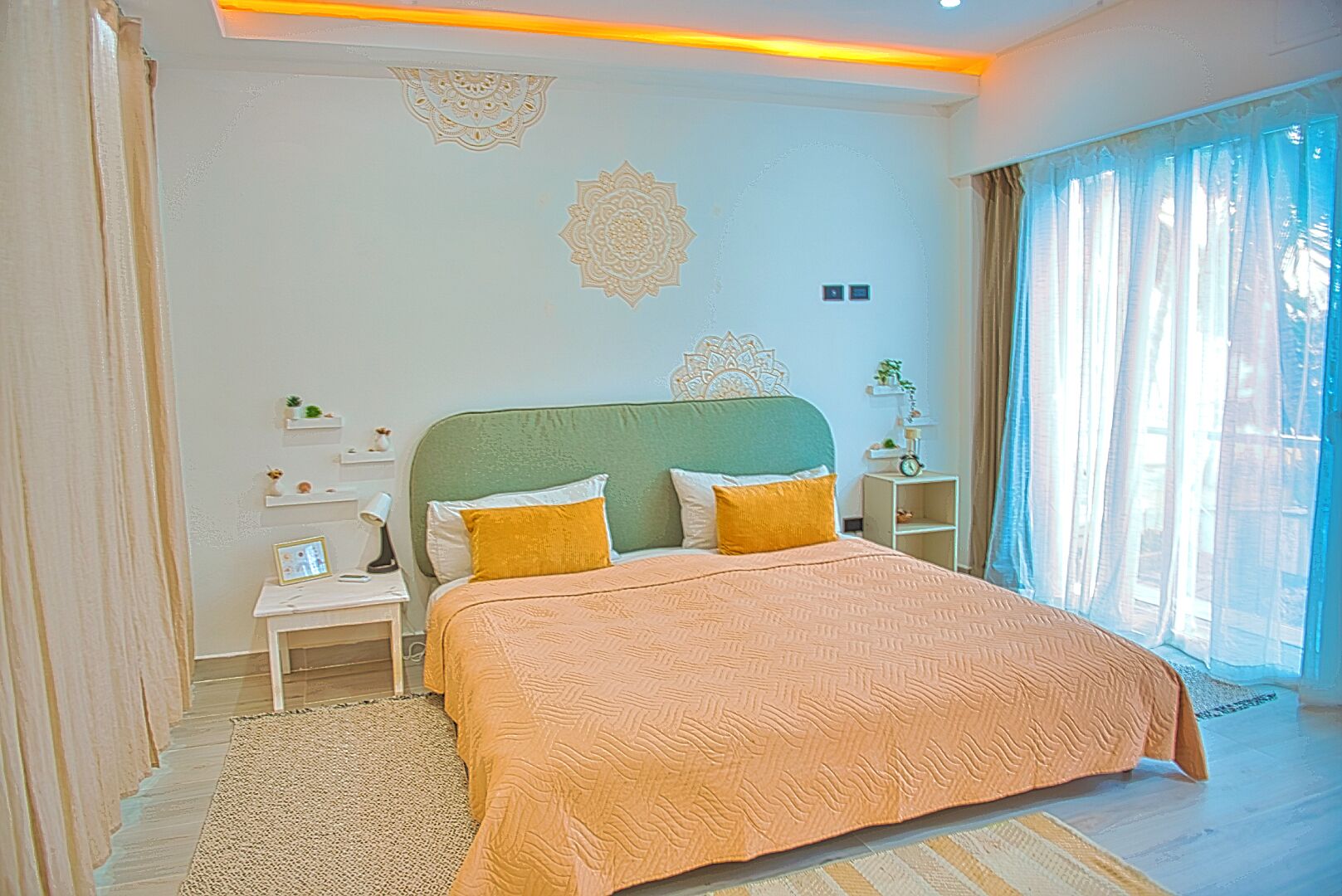 A bedroom with a bed, nightstands, a rug, and decorative wall patterns.