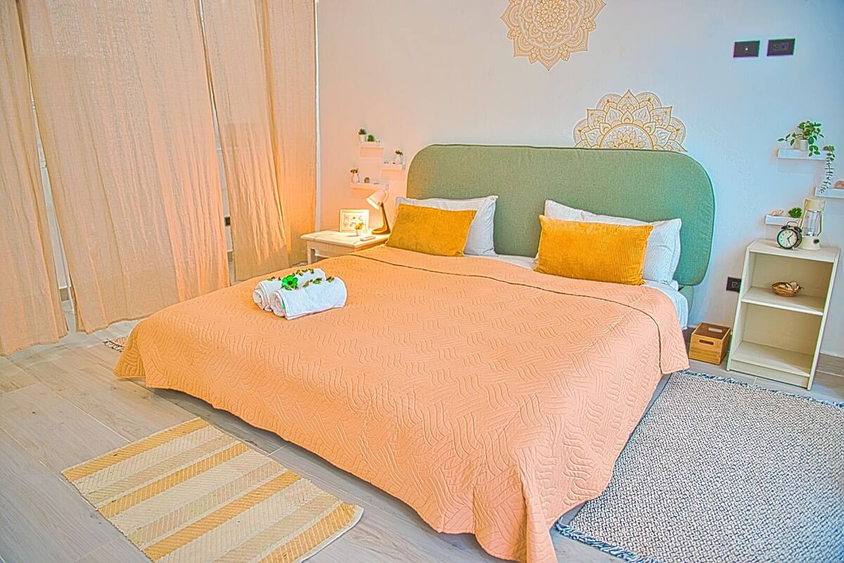 A neatly arranged bedroom with a bed, bedside tables, and a nightstand.