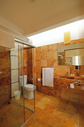 A modern bathroom with a glass-enclosed shower, a marble-tiled floor, a white toilet, and a large mirror above the sink. - Hotel Casa María  (Oaxaca)