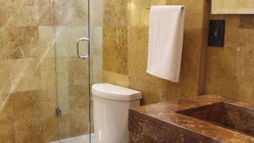 A bathroom with a toilet, a sink, and a glass shower enclosure.