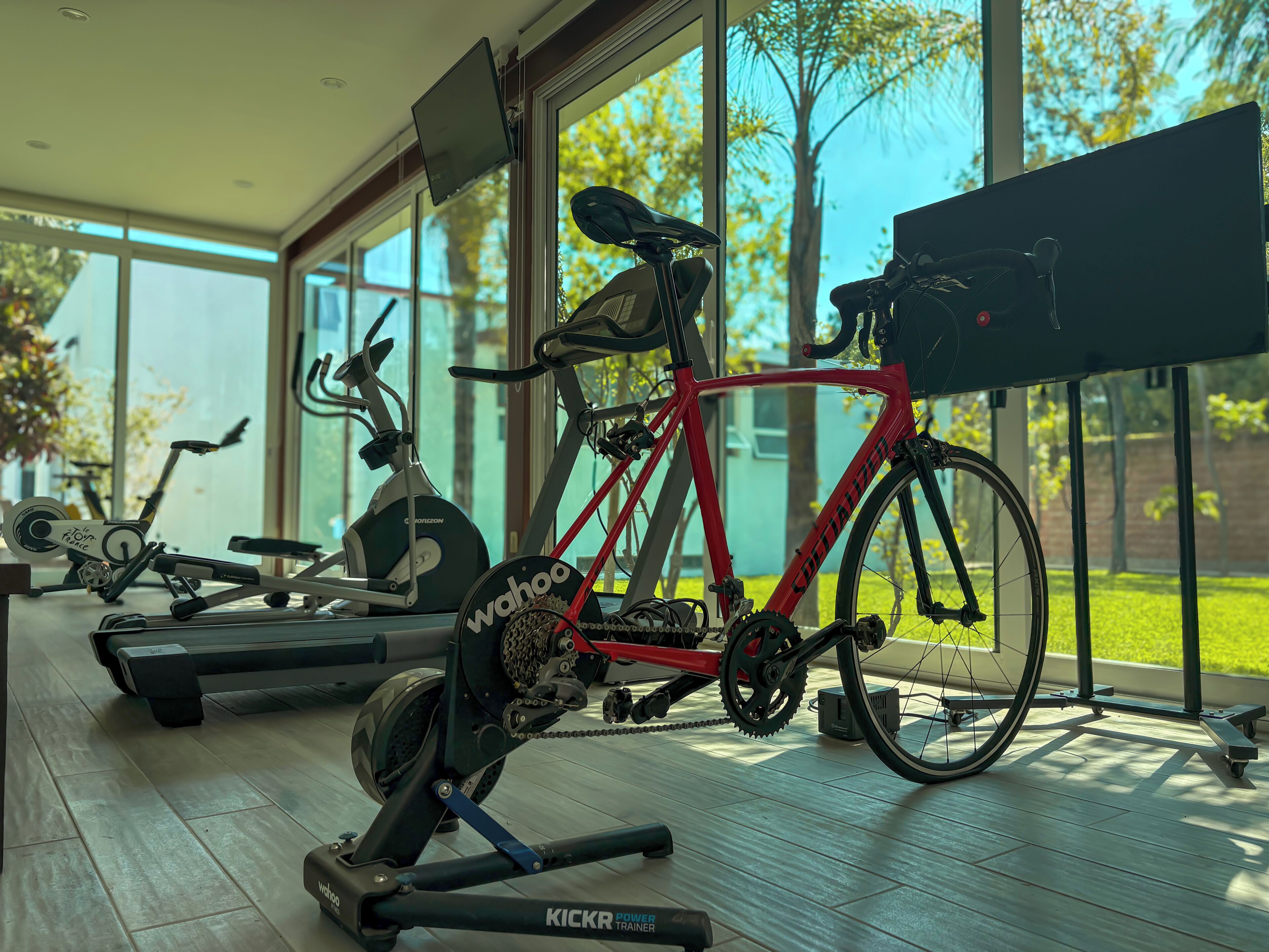 A home gym with exercise equipment including a stationary bike, treadmill, and elliptical machine.
