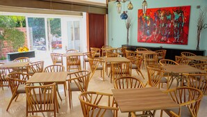 A spacious dining area with wooden tables and chairs, large windows, and a vibrant abstract painting on the wall. - Hotel Casa María  (Oaxaca)