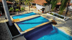 A swimming pool with a tiled deck, surrounded by potted plants and palm trees. - Hotel Casa María  (Oaxaca)