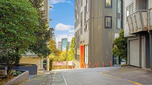 A modern urban street with buildings, a tree-lined sidewalk, and a clear sky. - City Skyline Apartment near Myers Park (Auckland)