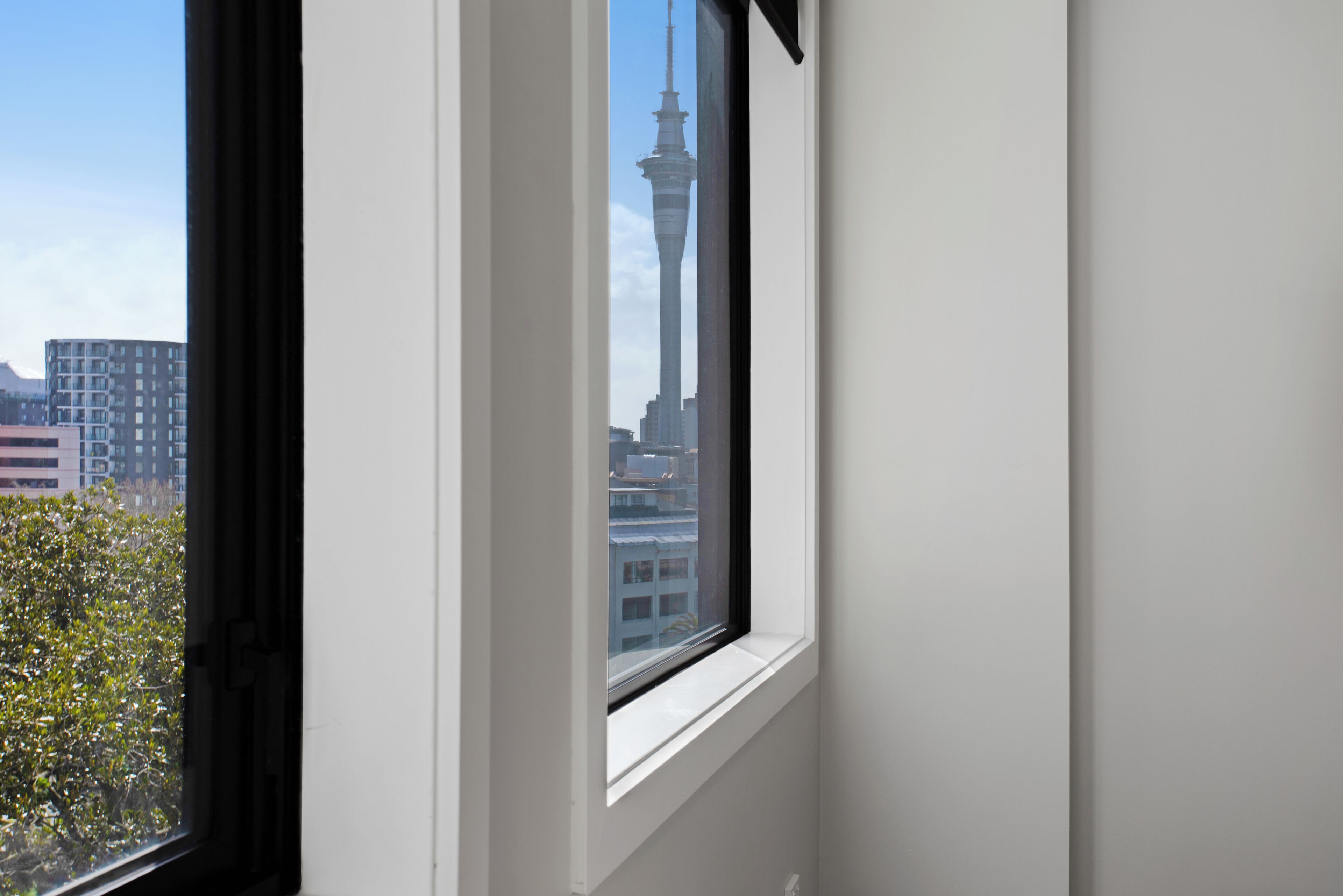 Janela com vista para uma torre alta e edifícios circundantes.