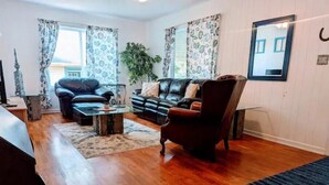 A living room with a leather sofa, a wooden coffee table, and a patterned rug.