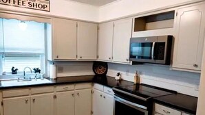 A kitchen with white cabinets, a black countertop, a microwave, an oven, and a dishwasher.