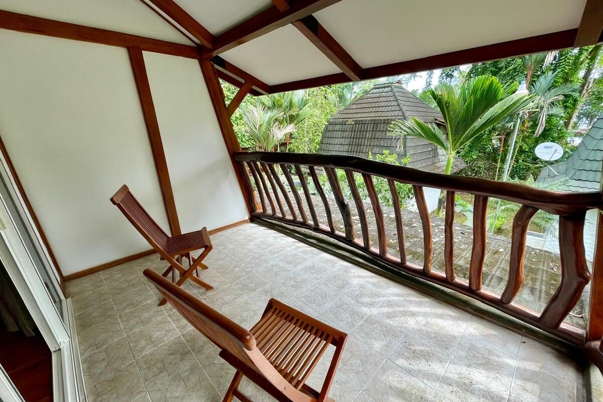 A balcony with wooden railings, a chair, and a tiled floor.