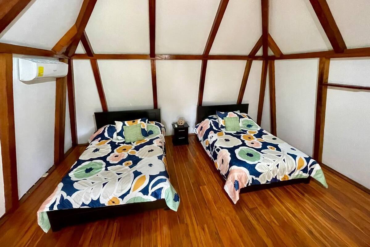 Ein Zimmer mit zwei Betten, Holzboden und einer schrägen Decke mit Holzbalken.