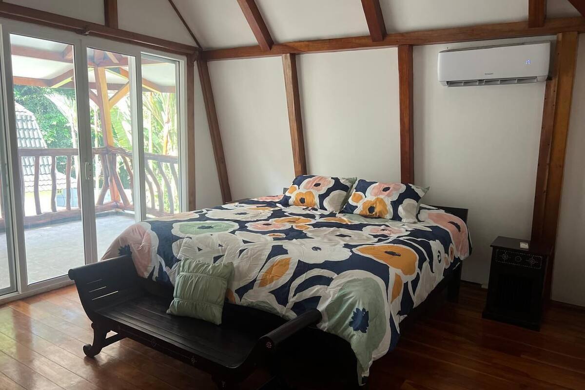 Ein Schlafzimmer mit einem Bett, einer Sitzbank und einer Klimaanlage.