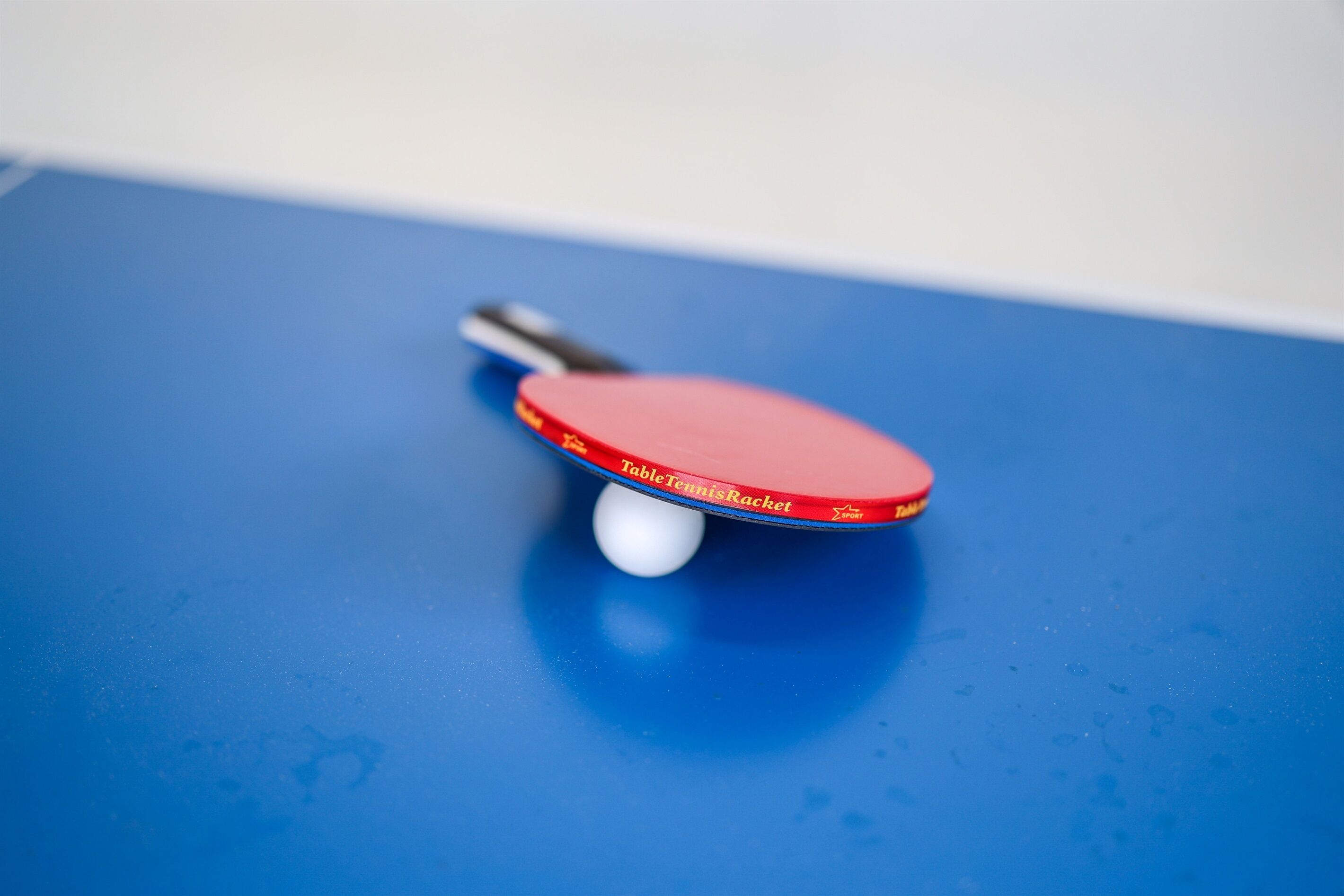 Una paleta de tenis de mesa sobre una superficie azul.