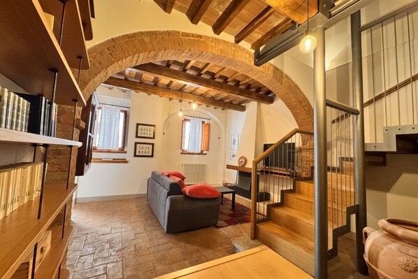 A cozy living area with a fireplace, a sofa, and a staircase with a metal railing.