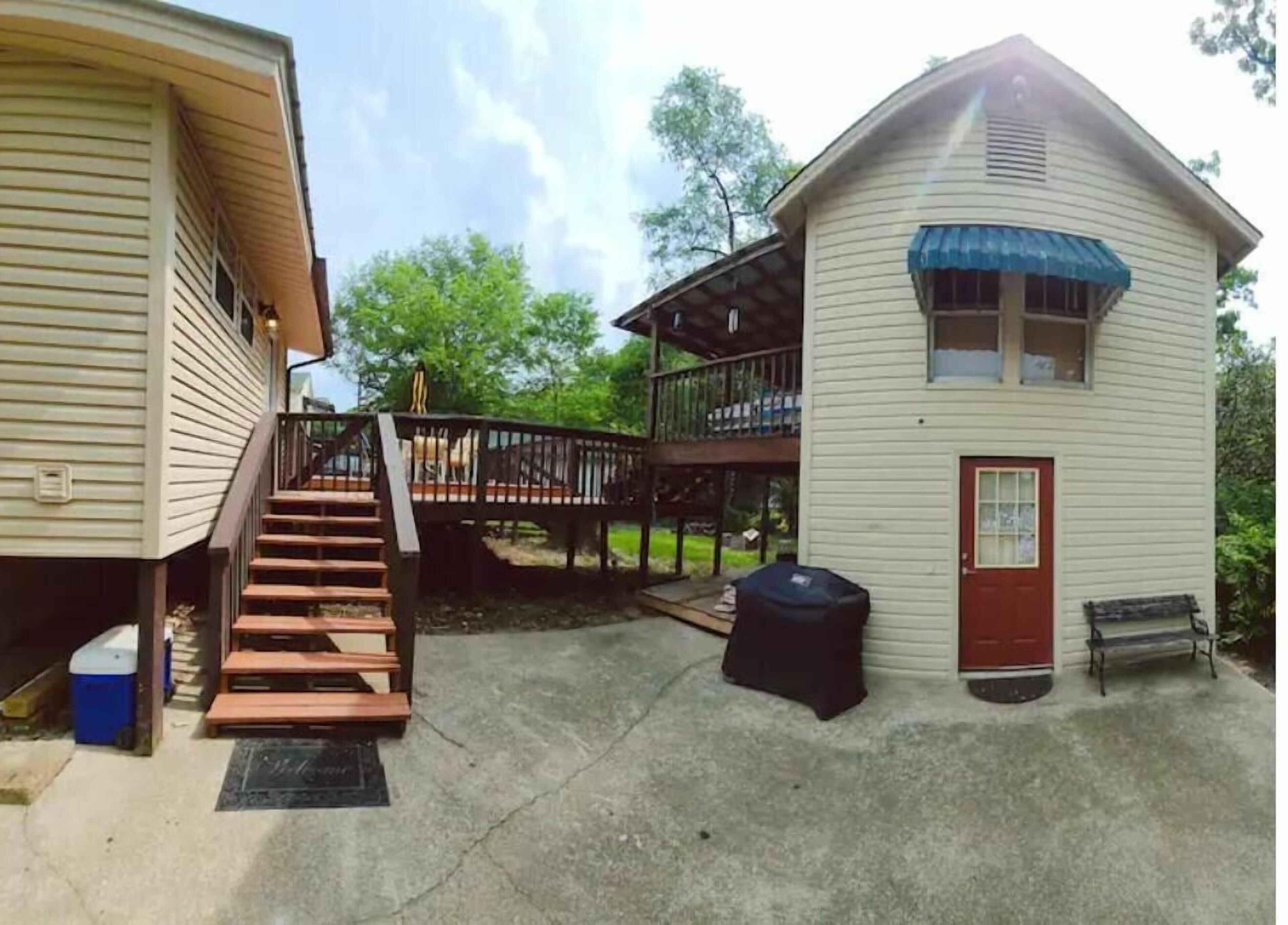 Ein zweigeschossiges Haus mit Veranda, Treppe und kleiner Terrasse.