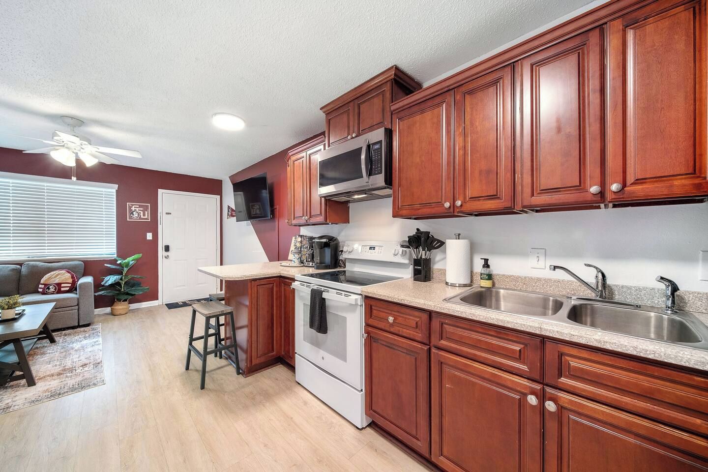 A kitchen with wooden cabinets, a microwave, a stove, and a sink.