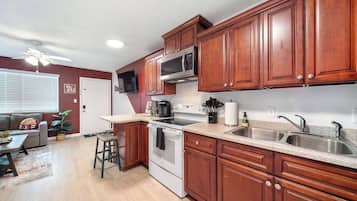 A kitchen with wooden cabinets, a microwave, a stove, and a sink.