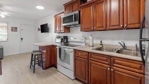 Una cocina con armarios de madera, microondas, estufa y lavamanos.
