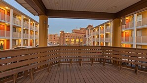 Un hotel con varios pisos, balcones y una zona de terraza de madera.