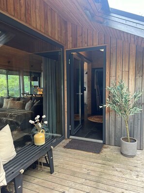 A wooden exterior with a glass door leading to a living area with a sofa and a coffee table.