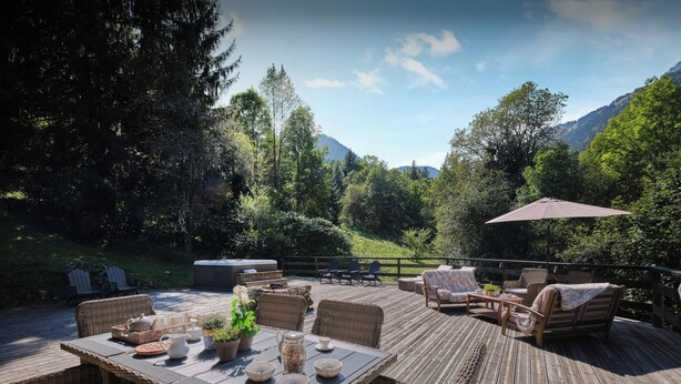 A deck with wicker furniture, a hot tub, and a view of mountains. - Chalet Fleur d'Aulps - Secluded holiday for 12 with spa - OVO Network (Saint-Jean-d'Aulps)