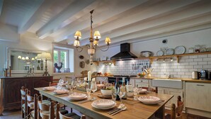 A well-lit kitchen with a dining table set for a meal, wooden chairs, and a chandelier. - Chalet Fleur d'Aulps - Secluded holiday for 12 with spa - OVO Network (Saint-Jean-d'Aulps)