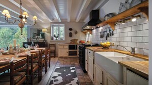 A kitchen with a dining area, wooden furniture, a cowhide rug, and a window with a view of greenery. - Chalet Fleur d'Aulps - Secluded holiday for 12 with spa - OVO Network (Saint-Jean-d'Aulps)