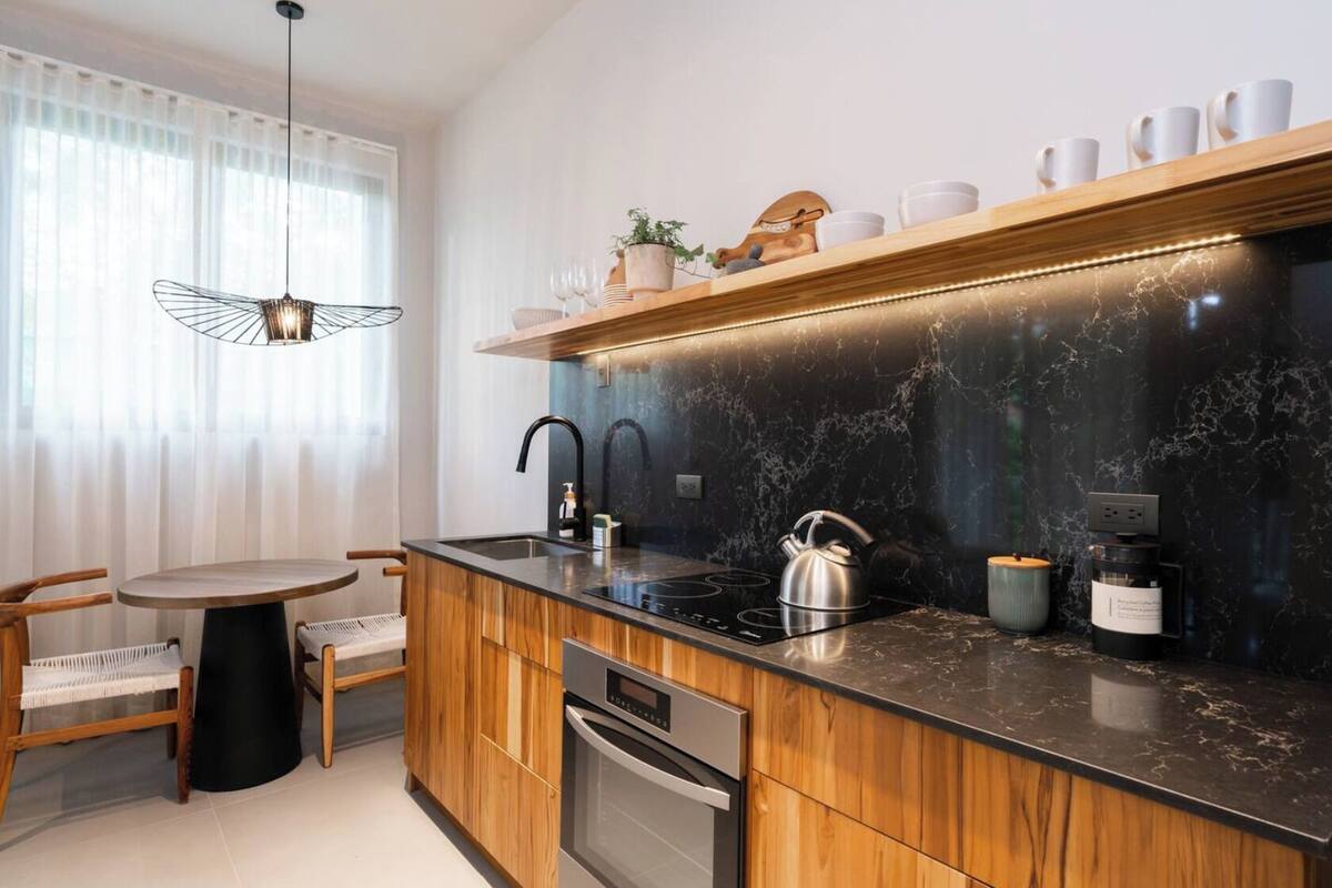 A modern kitchen with a wooden island, black countertop, and a built-in oven.