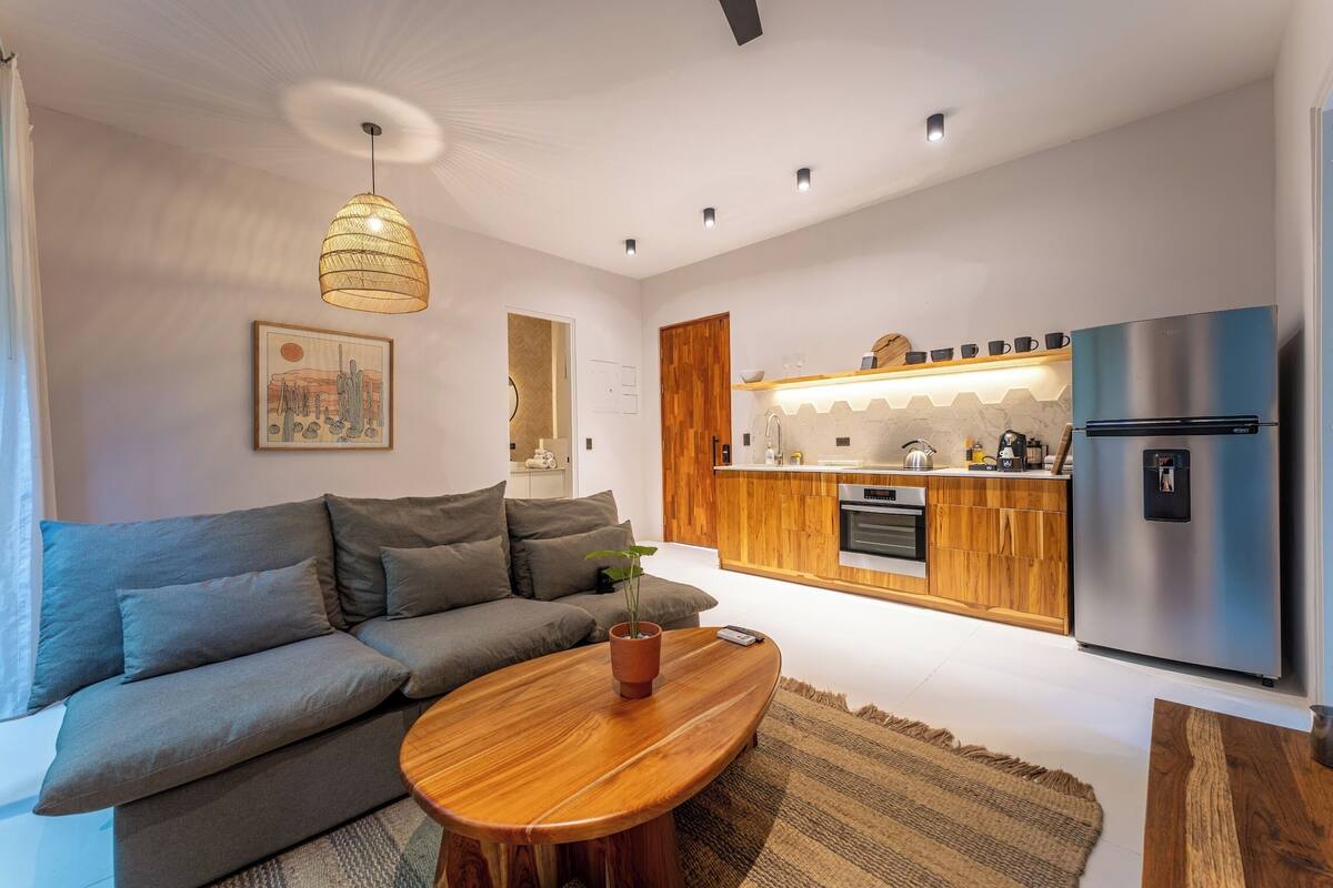 A modern living room with a sofa, a wooden coffee table, and a hanging light fixture.