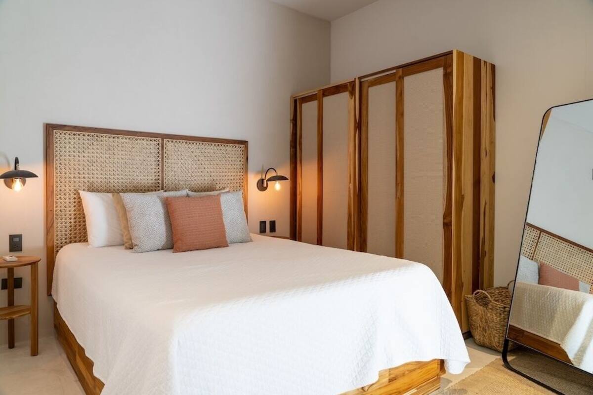 A bedroom with a large bed, a wooden wardrobe, and two bedside lamps.