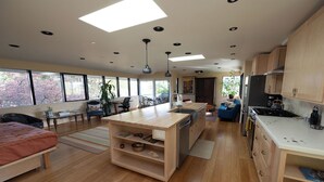 Una cocina moderna con armarios de madera, una isla central y un comedor con vistas a árboles.