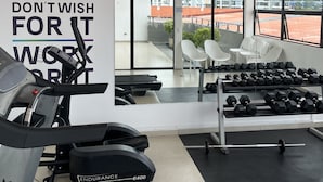 Un gimnasio con cintas de correr, mancuernas y una frase motivadora en la pared.