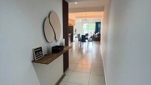 Un pasillo moderno con una recepción, un área de comedor al fondo y un espejo grande en la pared.