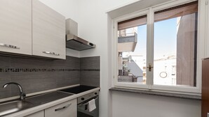 A modern kitchen with a stainless steel sink, a built-in oven, and a window with a view of buildings. - Charming Apartment with AC, WiFi close to St. Peter’s Square, Roma. (Roma)